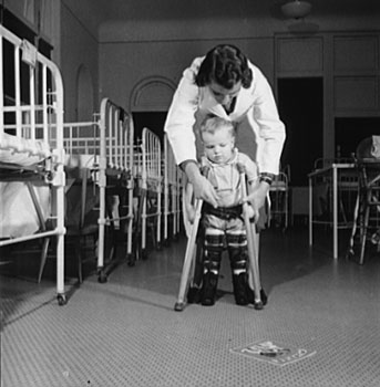 A student nurse encourages a young child to learn to use his crutches, with the help of a picture book (1942). (Library of Congress, LC-USE6-D-006947)